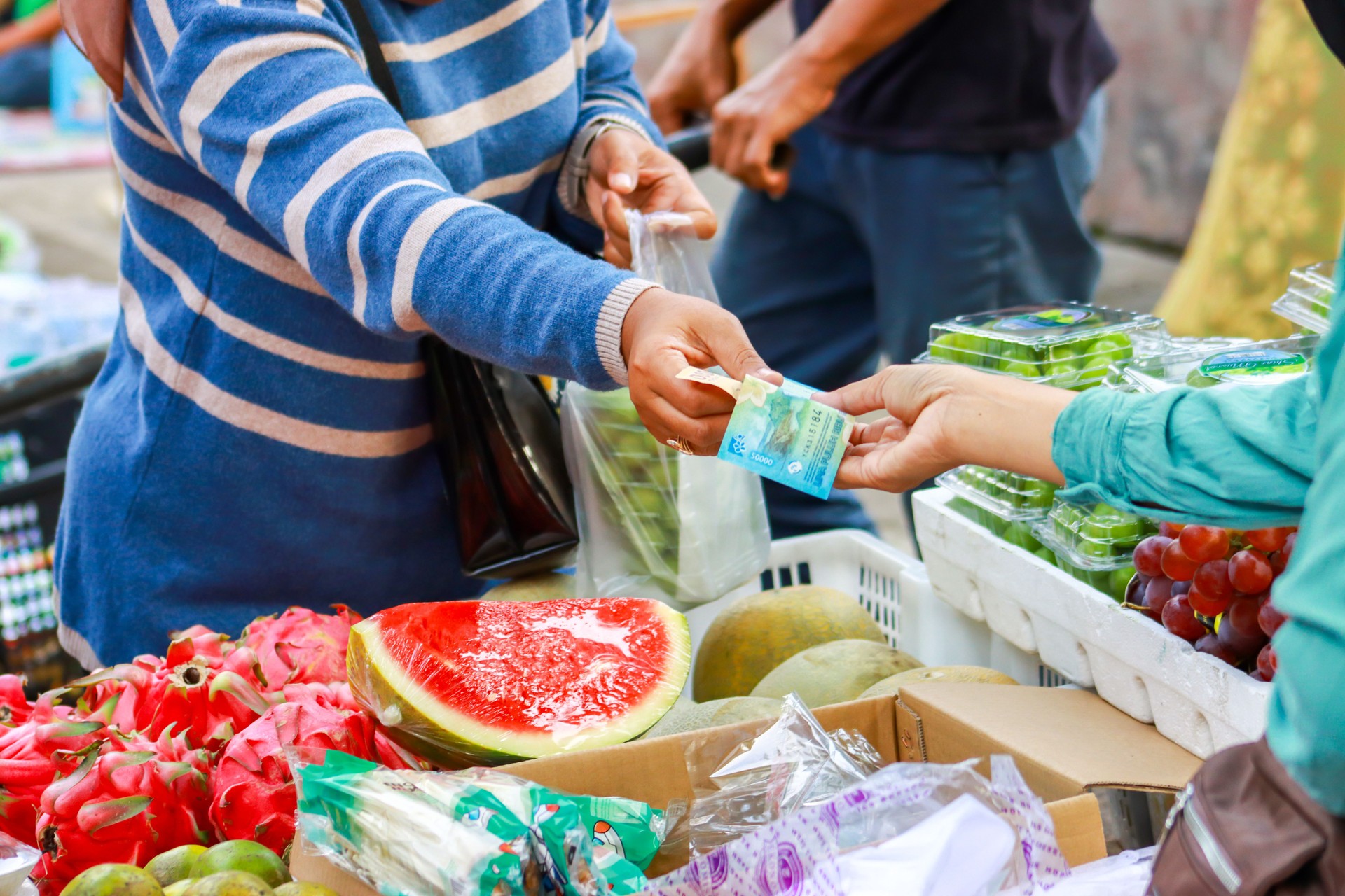 Buying and selling transactions at the market, buying fruit at the market with Indonesian currency.